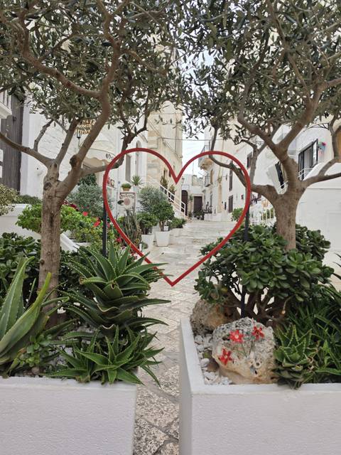 Decorative red heart frame looking onto a charming stone staircase lined with lush plants.