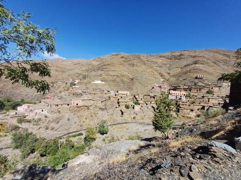Traditional Berber village of stone houses sprawled on a dry mountain slope.