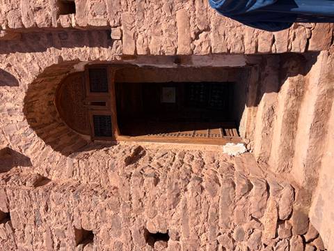 Stone doorway with wooden lintel and weathered steps leading into a shaded interior.
