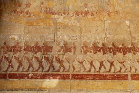 Ancient Egyptian wall relief of procession figures with faded pigments.