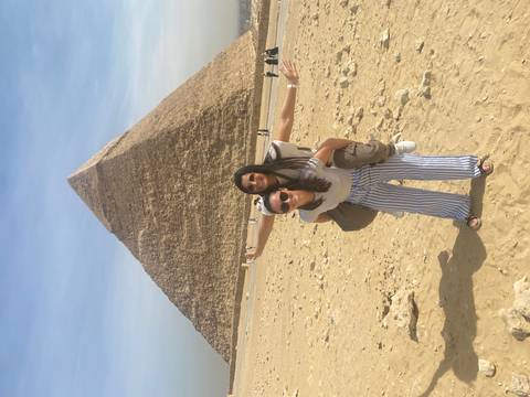 Playful piggyback pose in front of the Great Pyramid on sandy plateau.