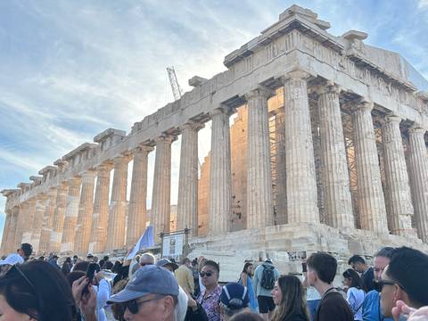 Crowds gather around the sun-lit columns of the Parthenon atop the Acropolis.
