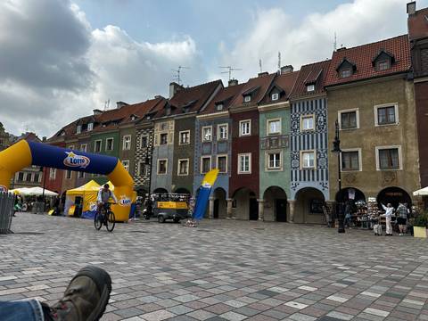 Colorful medieval merchant houses line Poznan’s Old Market Square with a cyclist passing an inflatable arch.