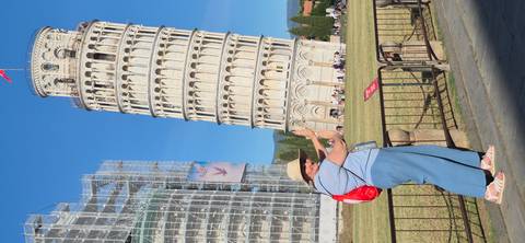 Traveller playfully poses as if holding up the Leaning Tower of Pisa.
