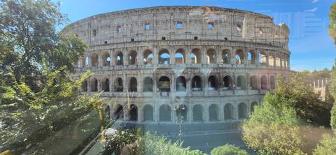 View of the Colosseum through reflective tour-bus glass on a sunny day.