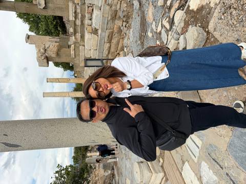 Playful couple strike poses amid fallen columns at an ancient archaeological site.