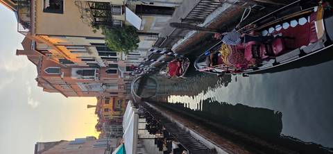 Serene Venetian canal at sunset with gondolier navigating beneath soft golden light.