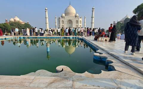 Large crowd lining the reflecting pool in front of the iconic Taj Mahal