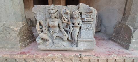 Stone sculpture of Hindu deities displayed on a plinth within an ancient complex