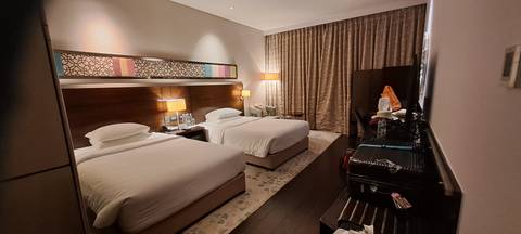 Modern hotel room with twin beds, warm lighting and neatly arranged amenities