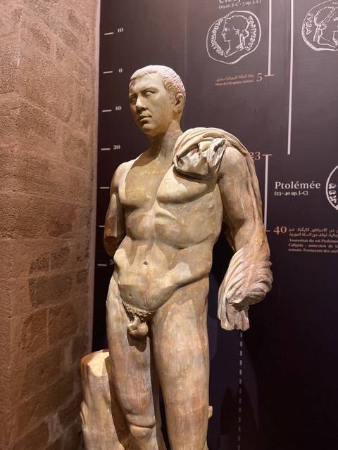 Classical marble statue displayed under focused lighting inside a museum gallery