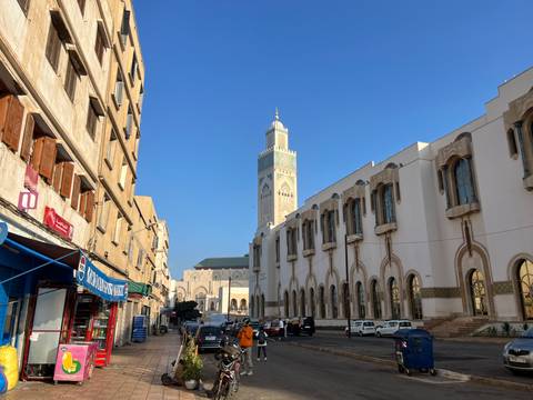 Minaret of Hassan II Mosque towers above modern city street bathed in morning light