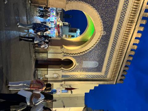 Night scene at the ornate Blue Gate with tourists milling under colorful lights