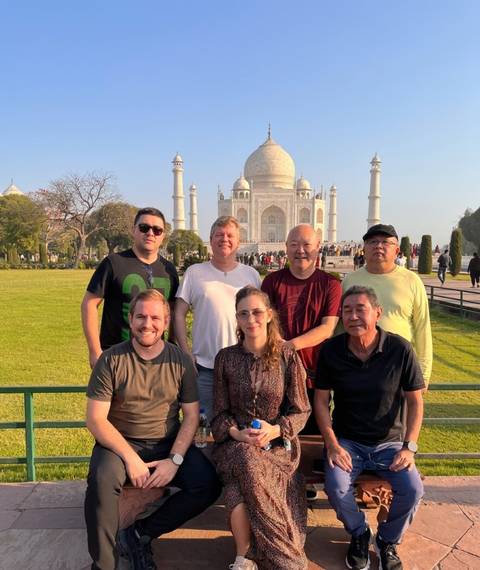 Group of travellers smiling with the Taj Mahal in the distant background
