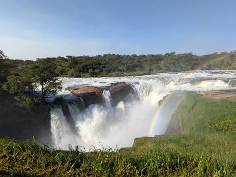 Powerful waterfall plunging into a gorge with mist and a vivid rainbow arching over the scene.