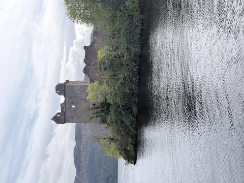 Ruins of Urquhart Castle situated on a promontory jutting into the dark waters of Loch Ness.