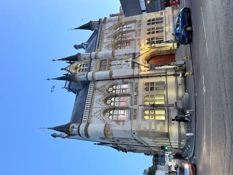 Elegant Victorian building with stained glass windows and spires illuminated at dusk on a city street.