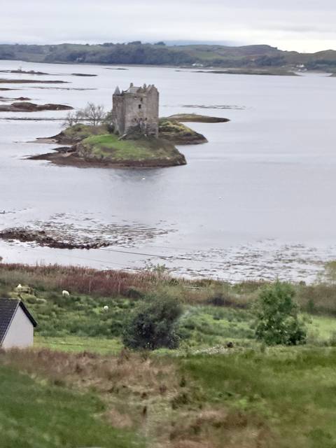 Blurry distant view of small islands and shoreline on a grey, misty loch.