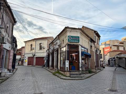 Narrow cobblestone street lined with historic shopfronts and overhead cables in Bitola’s old bazaar.