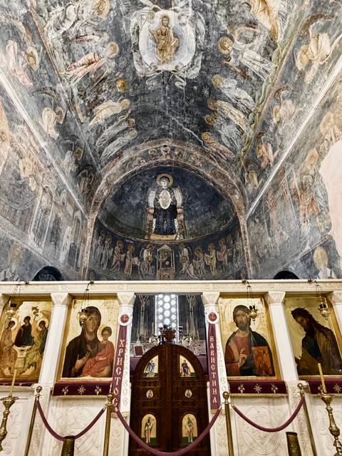 Byzantine church apse richly painted with dark medieval frescoes depicting biblical figures.