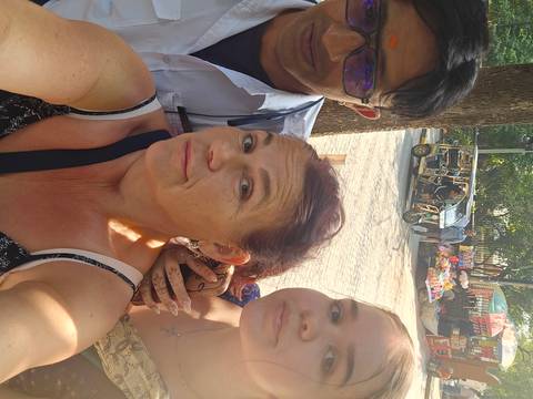 Close-up selfie of three travellers on a busy Indian street with an auto-rickshaw behind.