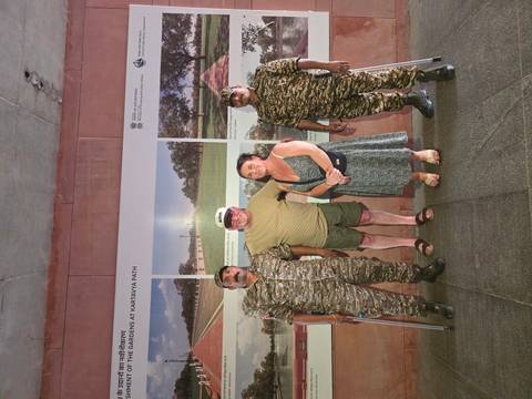 Tourists posing with two uniformed guards in front of a Kartavya Path display panel.