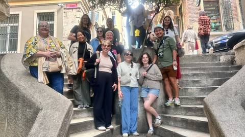 Tour group gathered on a historic stone staircase in an old Istanbul neighborhood smiling at the camera.