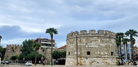 Stone Venetian tower and city walls rise beside palm-lined street in Durres.
