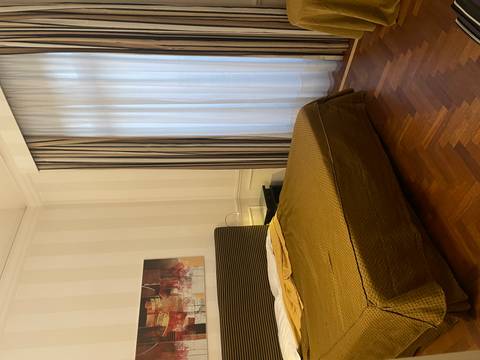 Simple hotel room with double bed, striped wallpaper and floor-length curtains.