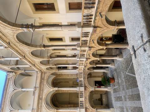 Elegant Renaissance cloister courtyard with arched colonnades and stone balustrades.