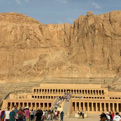 Temple of Hatshepsut set against towering desert cliffs under golden light.