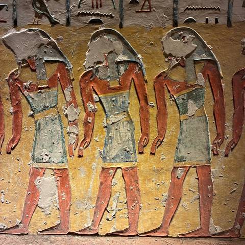 Fragment of ancient painted wall depicting three standing figures with faded plaster.
