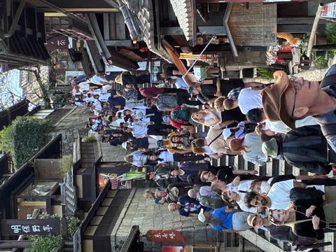 Dense crowd of tourists and students walk up a historic stone staircase lined with traditional wooden shops in Kyoto.