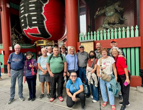 Tour group smiling beneath the giant red lantern of Kaminarimon gate at Senso-ji Temple.