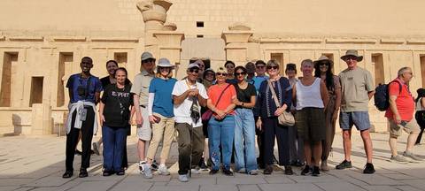 Tour group poses in front of the terraced façade of Hatshepsut Temple in Egypt.