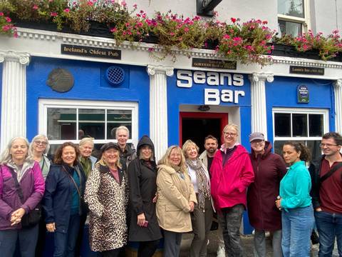 Happy tour group outside Sean's Bar, painted bright blue and labelled Ireland's oldest pub.