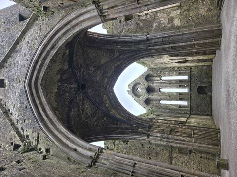 Soaring Gothic arch frames the empty nave of a ruined cathedral at the Rock of Cashel.