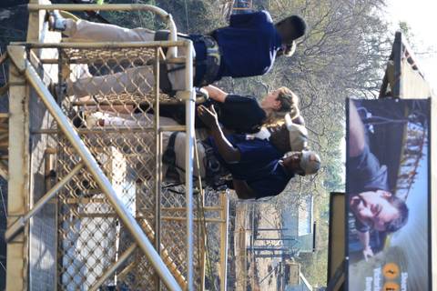 Guides assisting participants on a metal adventure deck above a gorge.
