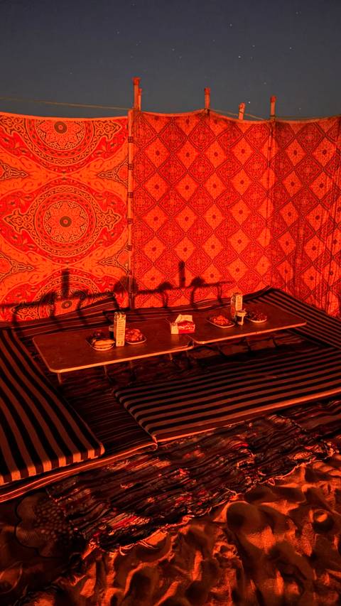 Low dining table with traditional dishes arranged inside a warmly lit desert tent.