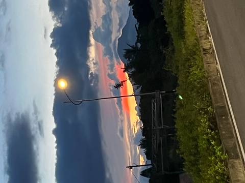 Twilight road scene with single streetlamp and dramatic cloud layers over distant hills.