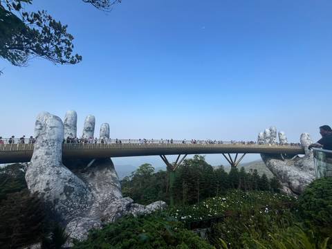 Iconic Golden Bridge supported by giant stone hands spanning forested valley.