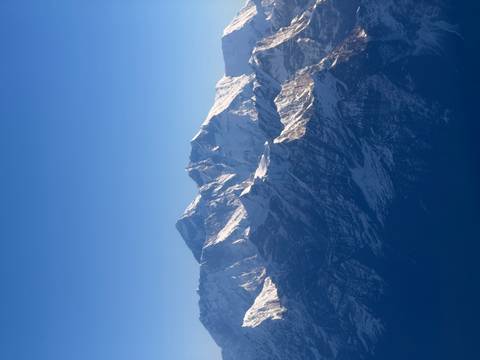 Majestic snow-covered Himalayan peaks rising against a clear deep-blue sky.