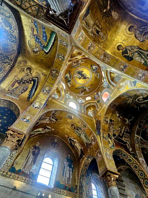 Golden Byzantine mosaics covering the domes and arches of Palermo’s Palatine Chapel with a beam of light streaming in.
