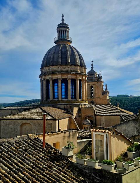 Ornate dome and bell tower of the Baroque San Giorgio Cathedral rising above tiled rooftops.