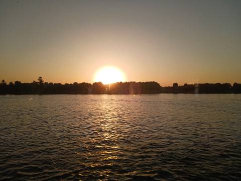 Golden sun setting over the Nile River casting reflections on calm water.