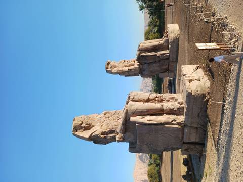 Morning light on the Colossi of Memnon statues towering over a lone visitor.
