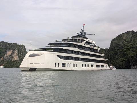 Modern white cruise ship anchored among limestone karsts in tranquil bay waters