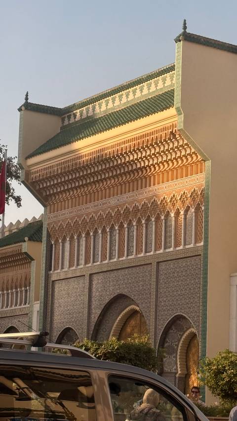 Detailed Islamic tile and stucco work on a royal Moroccan façade glowing in late light.