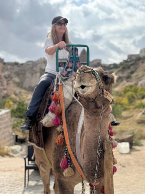 Close-up of a decorated camel with its rider against the rocky valleys of Cappadocia.
