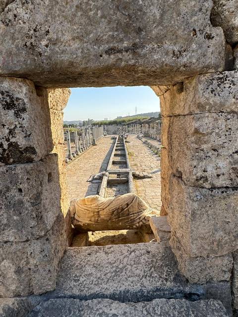 Ancient colonnaded street viewed through a stone archway at the Perga ruins.